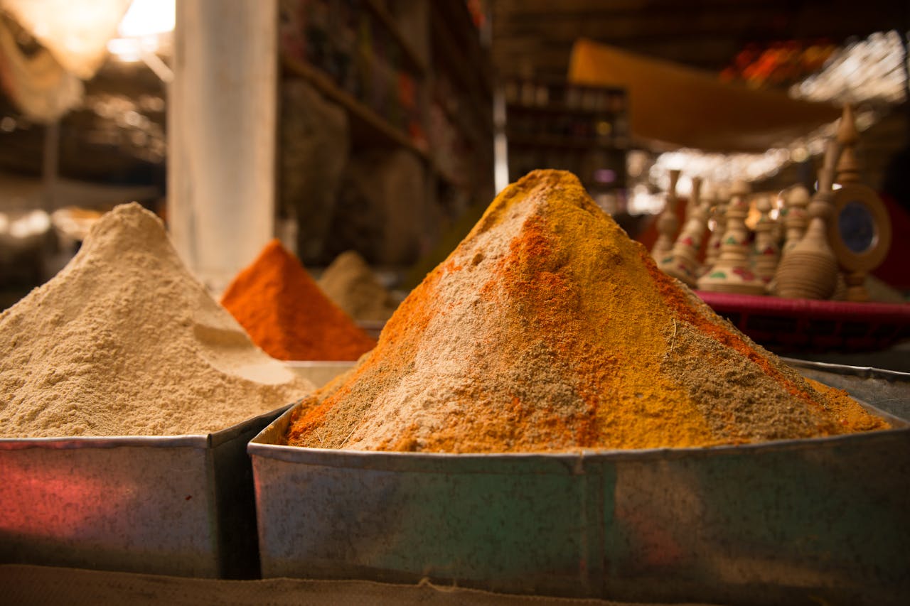Colorful spices in metal containers at an open-air market, offering a sensory feast.